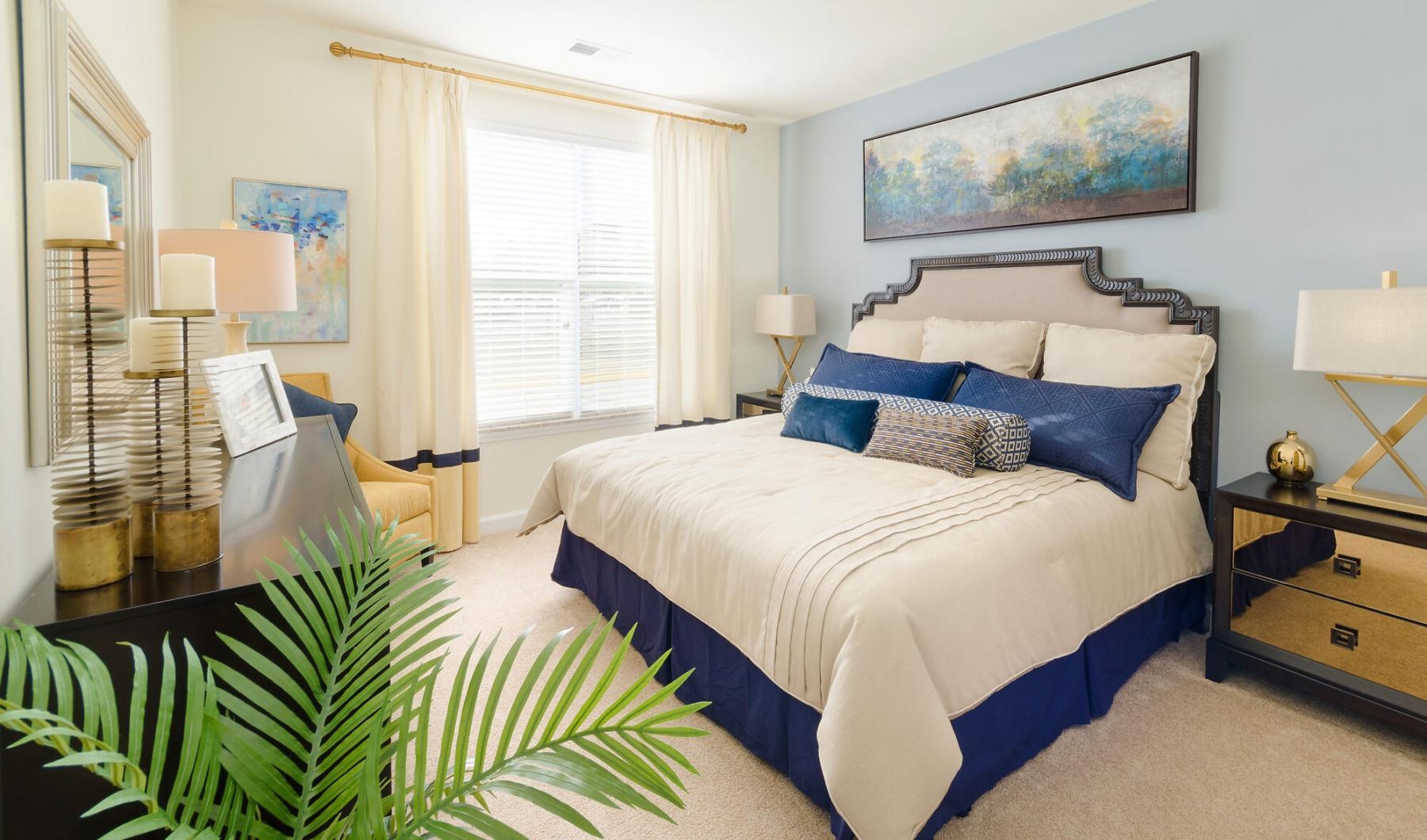 Generous bedroom offerings to fit every family Model bedroom at Victor Stonebridge Apartments in Woodbridge, VA, featuring carpeted flooring and windows with blinds.
