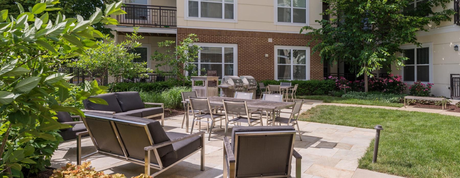 a patio with tables and chairs and plants in front of a building